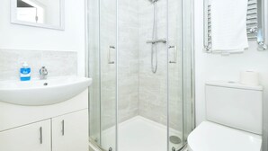 A modern bathroom with a glass-enclosed shower, a white sink, and a toilet. - Townhouse@ 147 Westminster Street Crewe (Crewe)