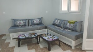 A corner room with a sofa and two small tables, a window, and a tiled floor. - Appartment F1 Bab El-assa (souk tlata)
