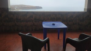 A room with a view of the sea, a table, and two chairs. - Appartment F1 Bab El-assa (souk tlata)