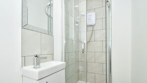 Ein modernes Badezimmer mit einer gläsernen Duschkabine, einem weißen Waschbecken und einem Spiegel.