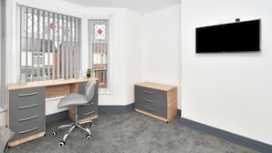 Ein moderner Arbeitsraum mit Schreibtisch, Stuhl und einem Wand-Fernseher.