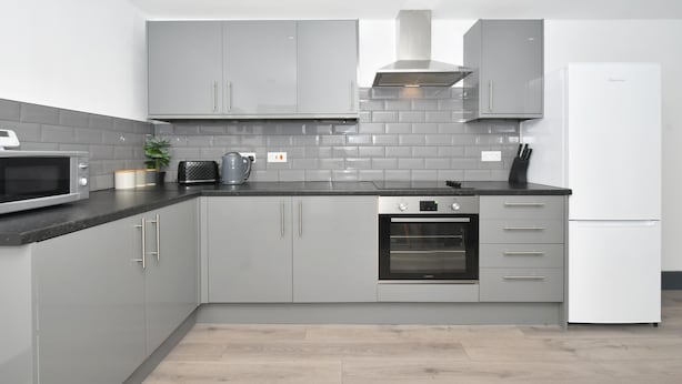 Eine moderne Küche mit grauen Schränken, einer Mikrowelle, einem Backofen und einem weißen Kühlschrank.