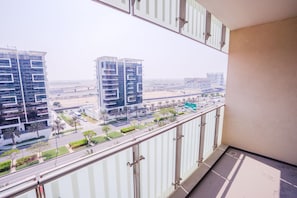 A balcony with a view of modern high-rise buildings and a road with palm trees.