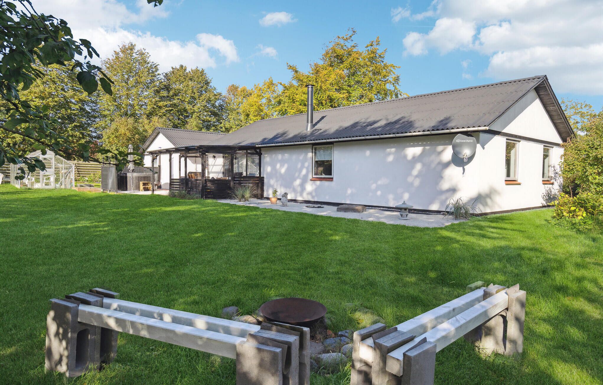 A modern house with a large patio, a covered outdoor seating area, and a satellite dish.