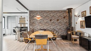 Un espace de repas moderne avec un mur en briques, une grande table en bois et des chaises contemporaines.