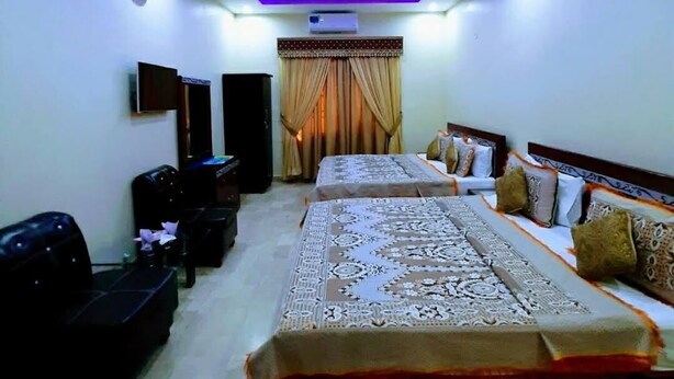 A modern bedroom with a large bed, a flat-screen TV, a ceiling fan, and a built-in air conditioning unit. - Galaxy Inn Millennium Mall (Karachi)
