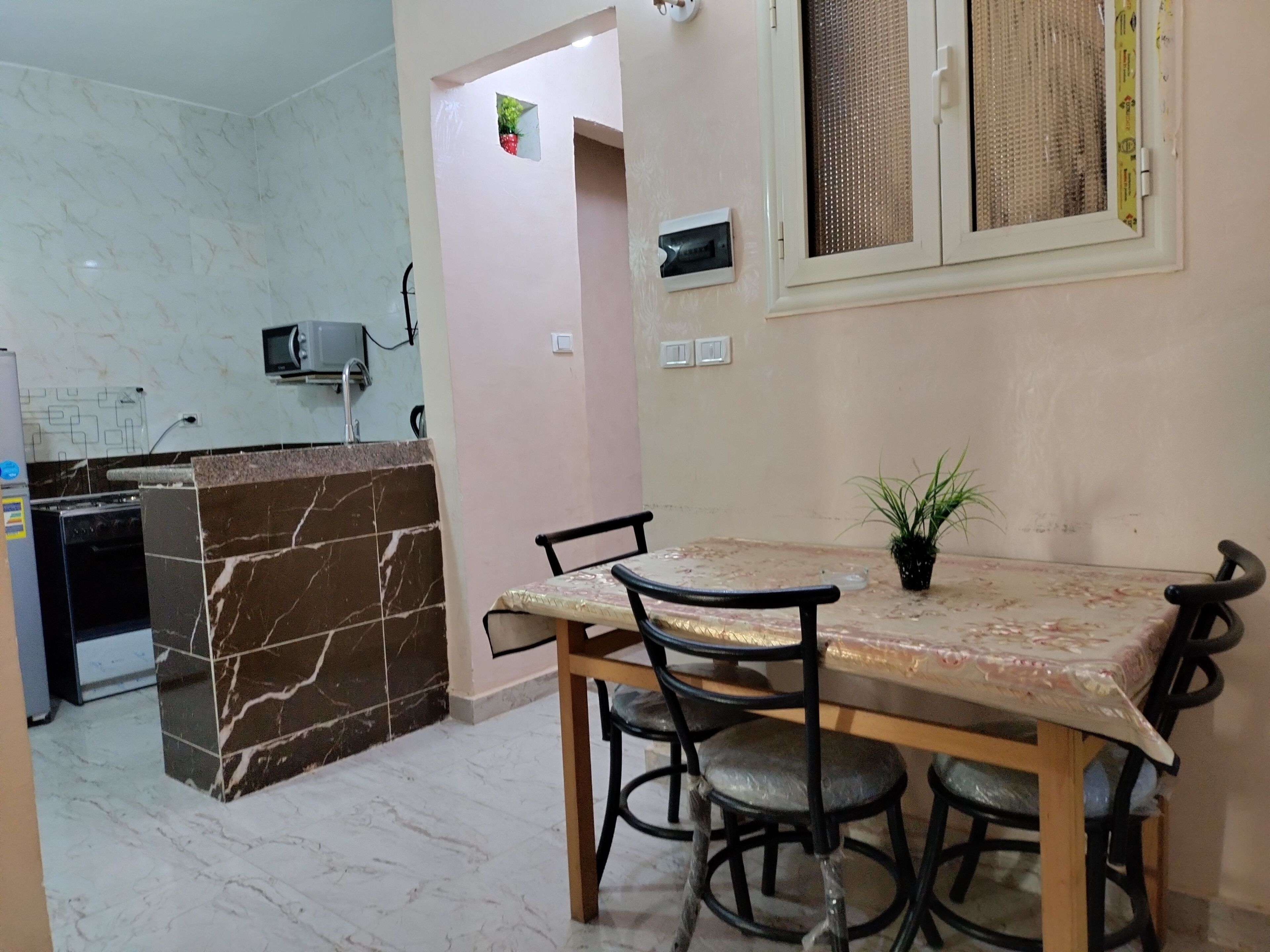 A kitchen with a marble backsplash, a built-in stove, and a microwave. There is a dining table with chairs and a potted plant.