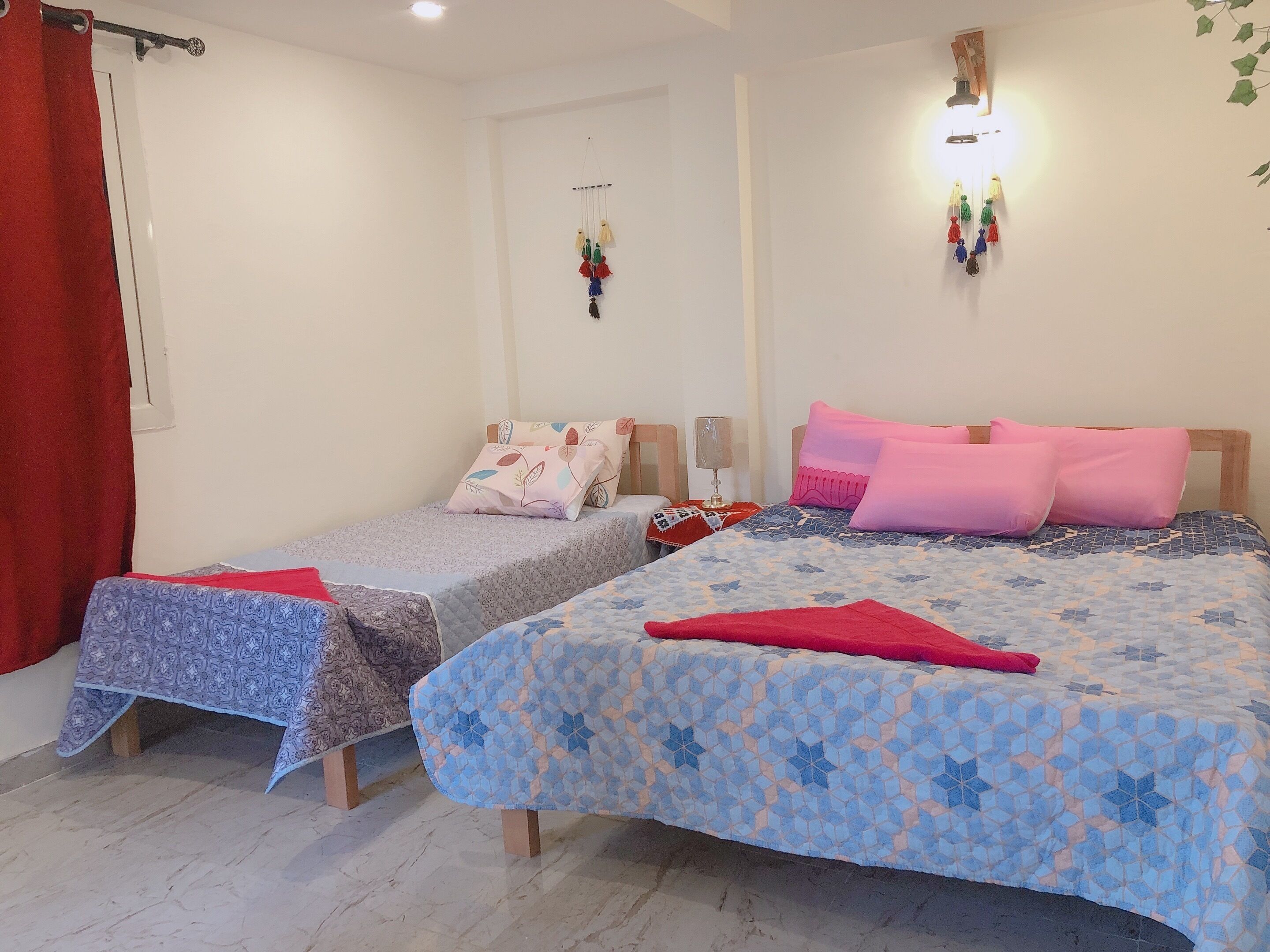 Een kamer met twee bedden, elk voorzien van beddengoed en kussens met een patroon. Er zijn wandlampen en een klein decoratief object aan de muur.