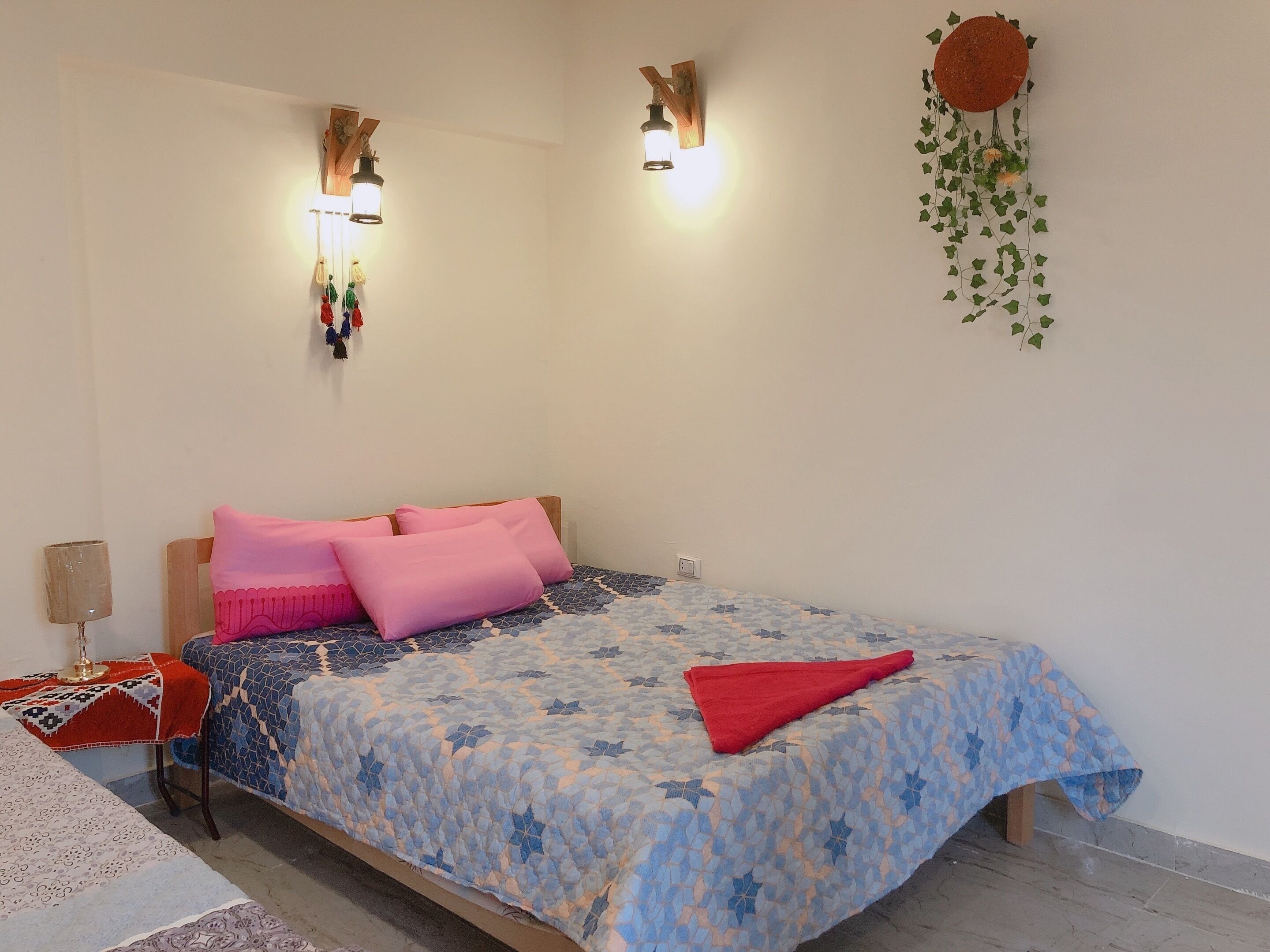 Une chambre à coucher avec un lit, des oreillers, une table de chevet, une lampe et des lampes fixées au mur.