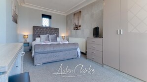 A bedroom with a large bed, bedside lamps, a dresser, a wardrobe, and a radiator. - Stunning Residence set on Cliffside in Scarborough (Scarborough)