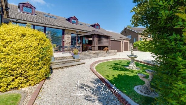 A modern house with a covered patio, a well-maintained lawn, and a decorative birdbath. - Stunning Residence set on Cliffside in Scarborough (Scarborough)