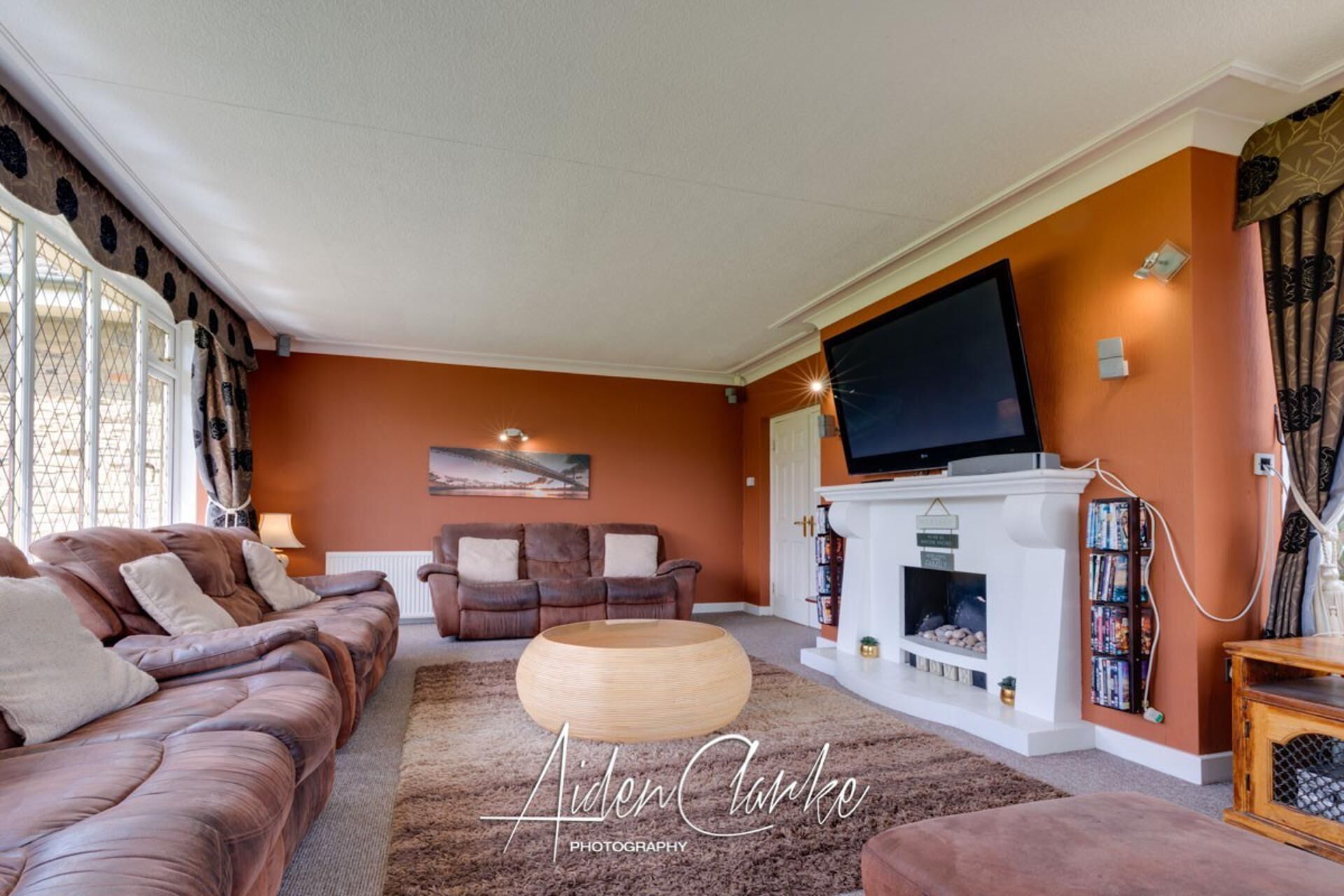 Een woonkamer met een open haard, banken, een televisie en een boekenkast.