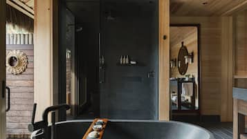 Un baño moderno con una bañera independiente, cabina de ducha de vidrio y paneles de madera.