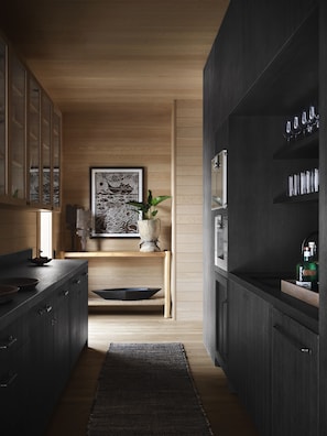 A modern kitchen with dark cabinetry, a wooden countertop, and a central island with a plant.