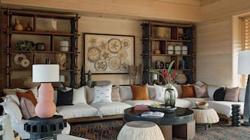 A cozy living room with a sofa, coffee table, and shelves filled with decorative items.