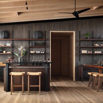 A modern kitchen with wooden shelves, a central island with stools, and a ceiling fan.