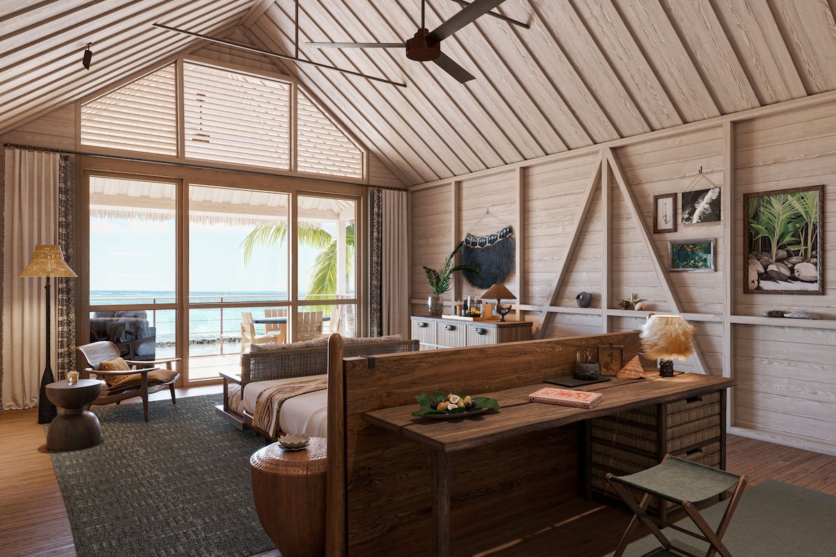 A spacious room with a large window overlooking the sea, a wooden ceiling, and a cozy seating area with a table and chairs.