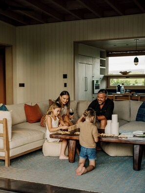 A family playing a board game in a cozy living room with a sofa, coffee table, and a view of the kitchen.