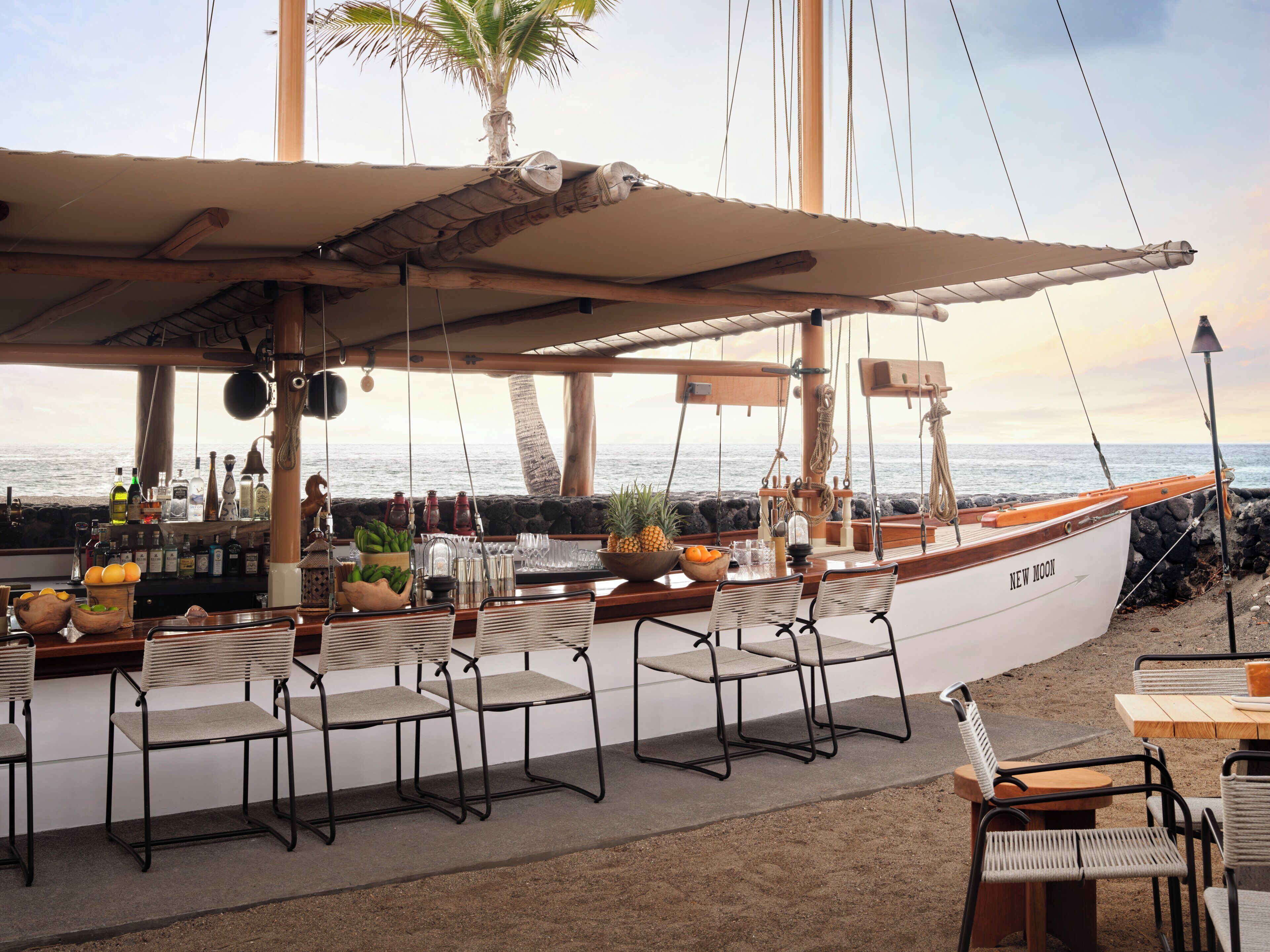 A bar area with a view of the ocean, equipped with bar stools and a wooden table.