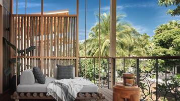 Un terrazza in legno con un'area salotto imbottita, un piccolo tavolino e vista su palme.