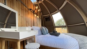 A cozy interior with a bed, a small desk, and a chair. - Sunrise Dome Tent (Tenby)