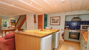 A modern kitchen with a wooden island, built-in appliances, and a blue-tiled backsplash. - Penybont Apartment (Aberystwyth)