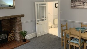 A living room with a fireplace, a dining area with a wooden table and chairs, and a door leading to another room. - Hursley Lodge (Lincoln)
