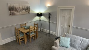 A cozy living room with a dining table, a sofa, a floor lamp, and a door. - Hursley Lodge (Lincoln)