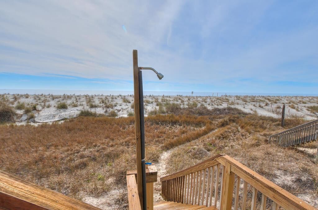 A wooden staircase leading to a sandy beach with a metal lamp post.
