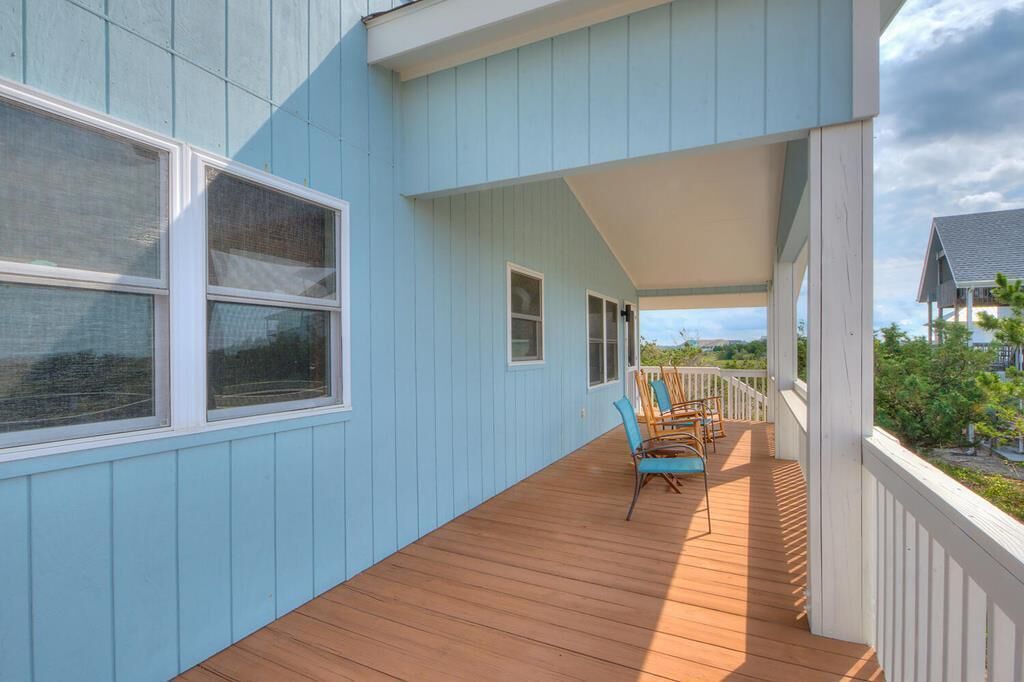 A covered wooden deck with a view of the surrounding landscape.