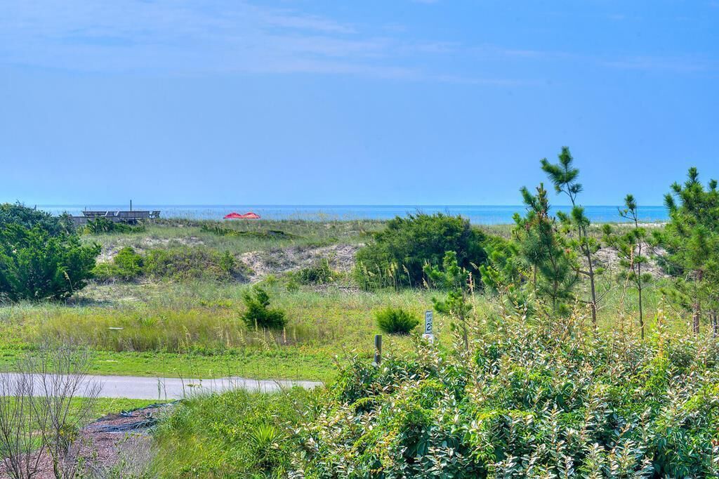 Eine Küstenlandschaft mit blauem Himmel, einer Straße und vereinzelter Vegetation.