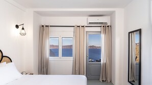 Habitación de hotel con cama, ventana con cortinas, equipo de aire acondicionado y vista al mar.
