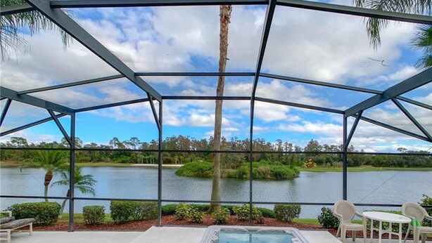 A pool area with a hot tub, surrounded by a covered patio with chairs, overlooking a lake and greenery. - Disney 6-bed Pool-spa Villa in Kissimmee, US (Kissimmee)