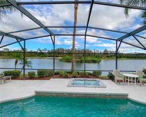 A pool area with a hot tub, surrounded by a covered patio with chairs, overlooking a lake and greenery. - Disney 6-bed Pool-spa Villa in Kissimmee, US (Kissimmee)