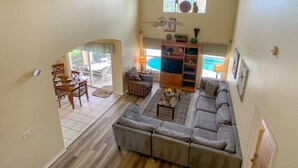 A spacious living room with a large sofa, a dining area with chairs, a pool view, and a bookshelf. - Disney 6-bed Pool-spa Villa in Kissimmee, US (Kissimmee)