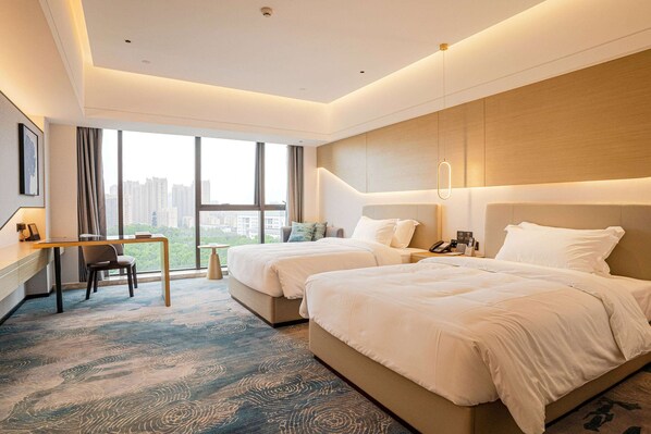 Une chambre d’hôtel avec deux lits, un bureau et une vue sur la ville.