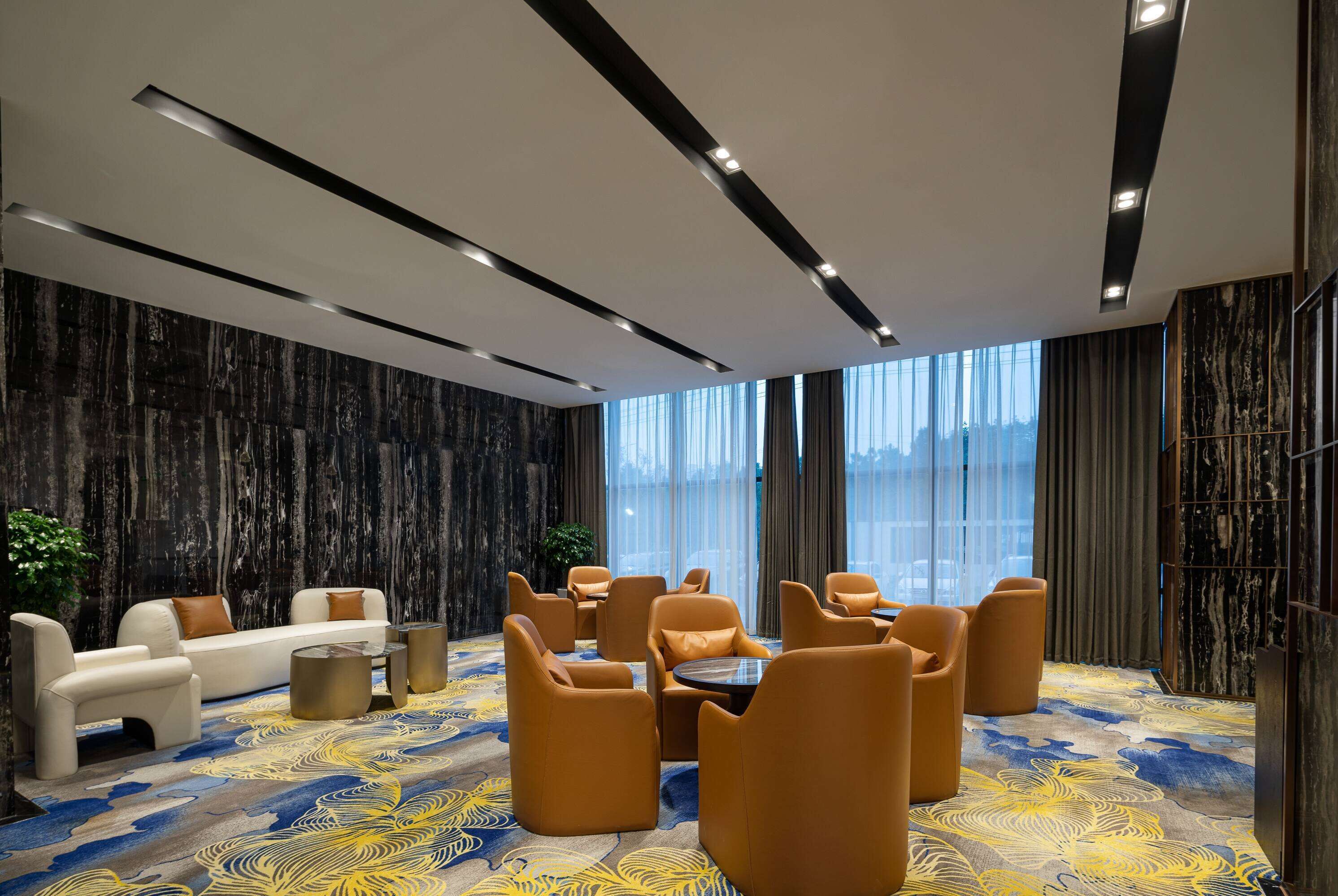 A modern hotel lobby with a sofa, chairs, and a coffee table.