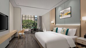 A modern hotel room with a large bed, a desk, and a TV. - Ramada Encore by Wyndham Xishuangbanna Jinghong (Xishuangbanna Dai)