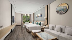 A modern hotel room with a large bed, a sofa, a TV, a dining table, and a view of greenery outside. - Ramada Encore by Wyndham Xishuangbanna Jinghong (Xishuangbanna Dai)