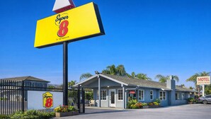 A motel with a prominent 'Super 8' sign, a small office, and a fenced parking area.