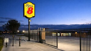 A Super 8 hotel entrance with a gated driveway, a clear sky, and a well-lit pathway.