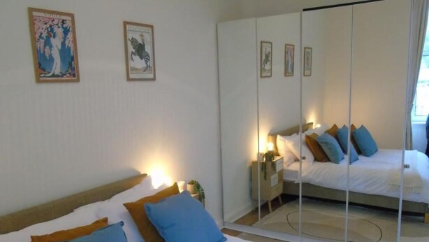 A hotel room with a large bed, a mirror, and artwork on the walls. - Snug - Tearlag Apartment (Helensburgh)