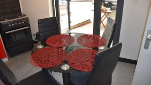 Een eethoek met een tafel voor vier personen, omringd door stoelen, en een keuken met een fornuis en oven.