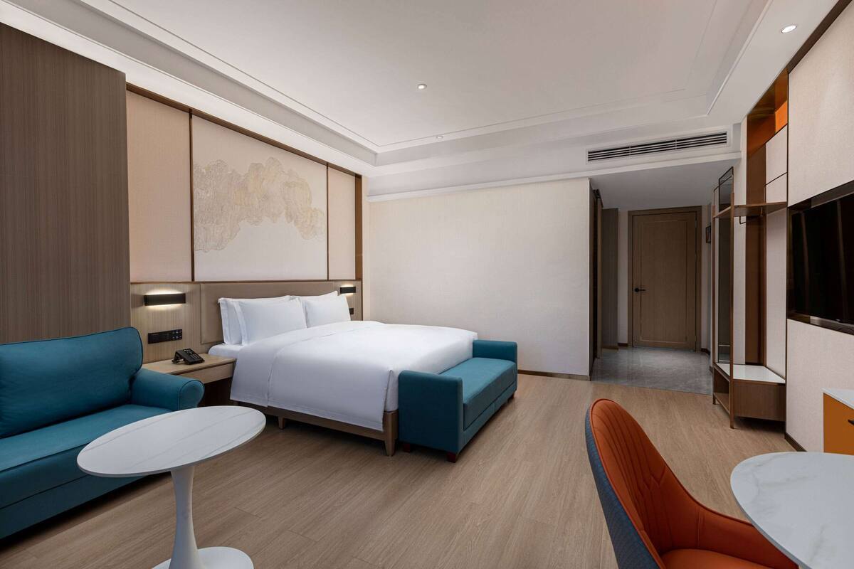 Une chambre d’hôtel moderne équipée d’un lit, d’un canapé, d’une petite table et d’un téléviseur.