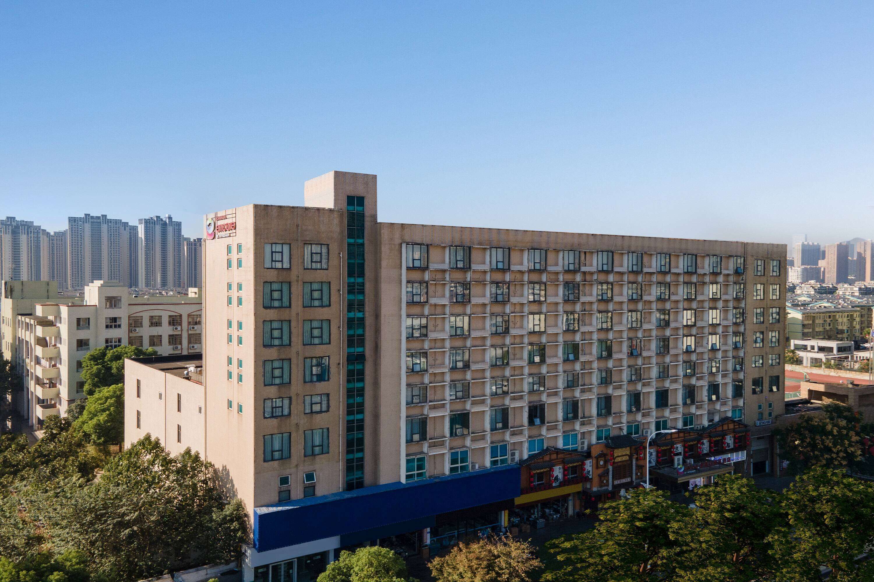 A multi-story hotel with a modern architectural design, featuring a prominent corner entrance and a series of balconies.