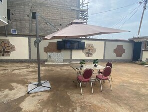 An outdoor patio with a table and chairs, a large umbrella, and a wall with decorative tiles.