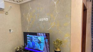 Un téléviseur posé sur un meuble noir, avec un mur en marbre en arrière-plan.
