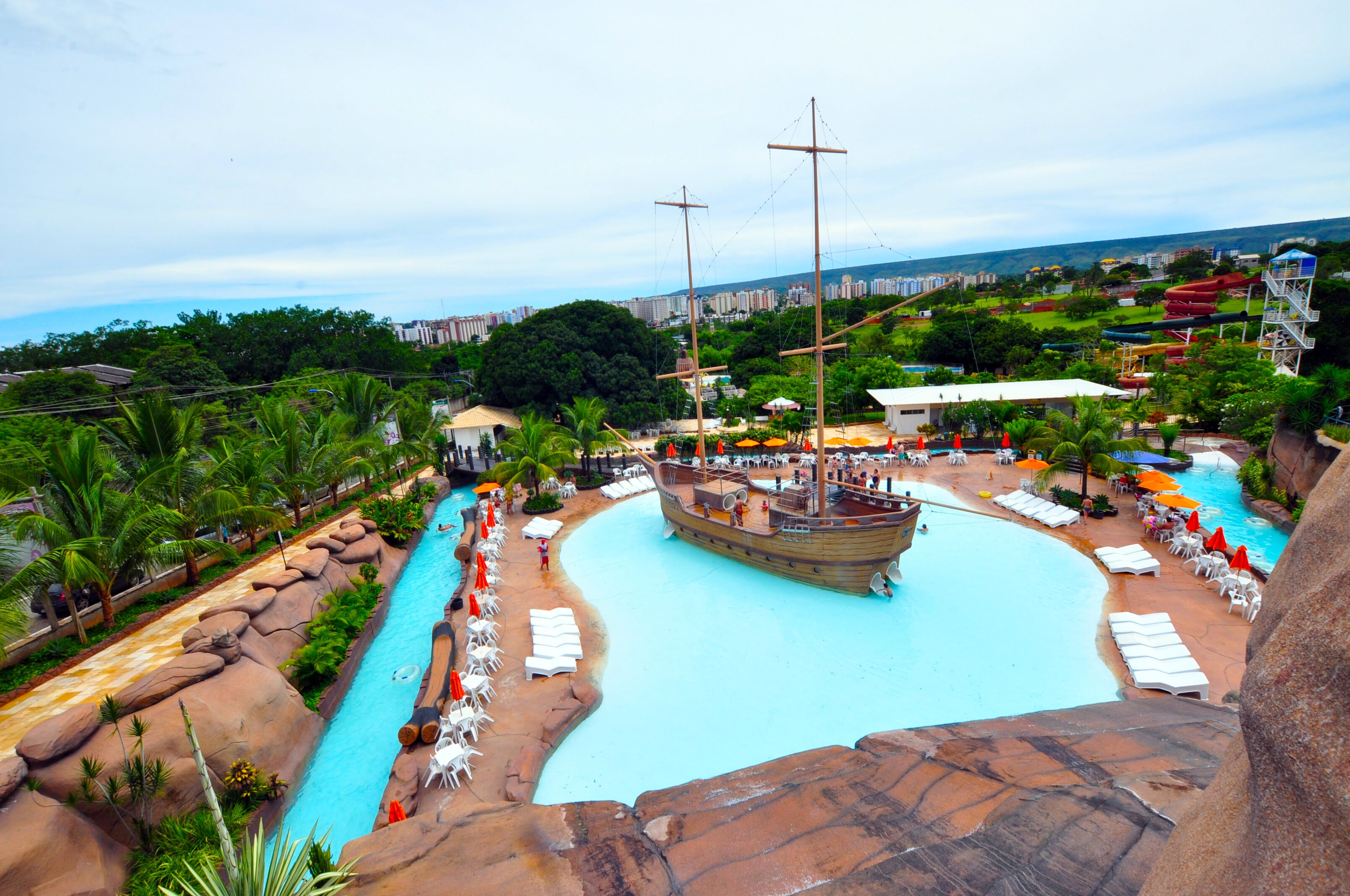 Ein Resort mit großem Pool, Piratenschiff und Blick auf die Stadt.
