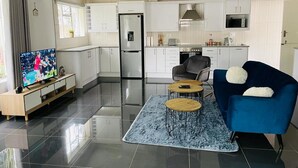 Un salon moderne avec un téléviseur à écran plat, un canapé bleu et une table basse.