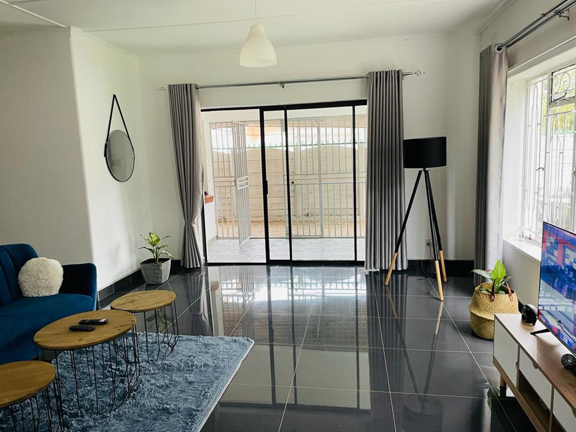 Un salon moderne avec un canapé bleu, une table basse, un téléviseur et un balcon offrant une vue agréable.